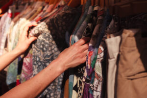 A young woman is browsing a rail of clothes at a street market